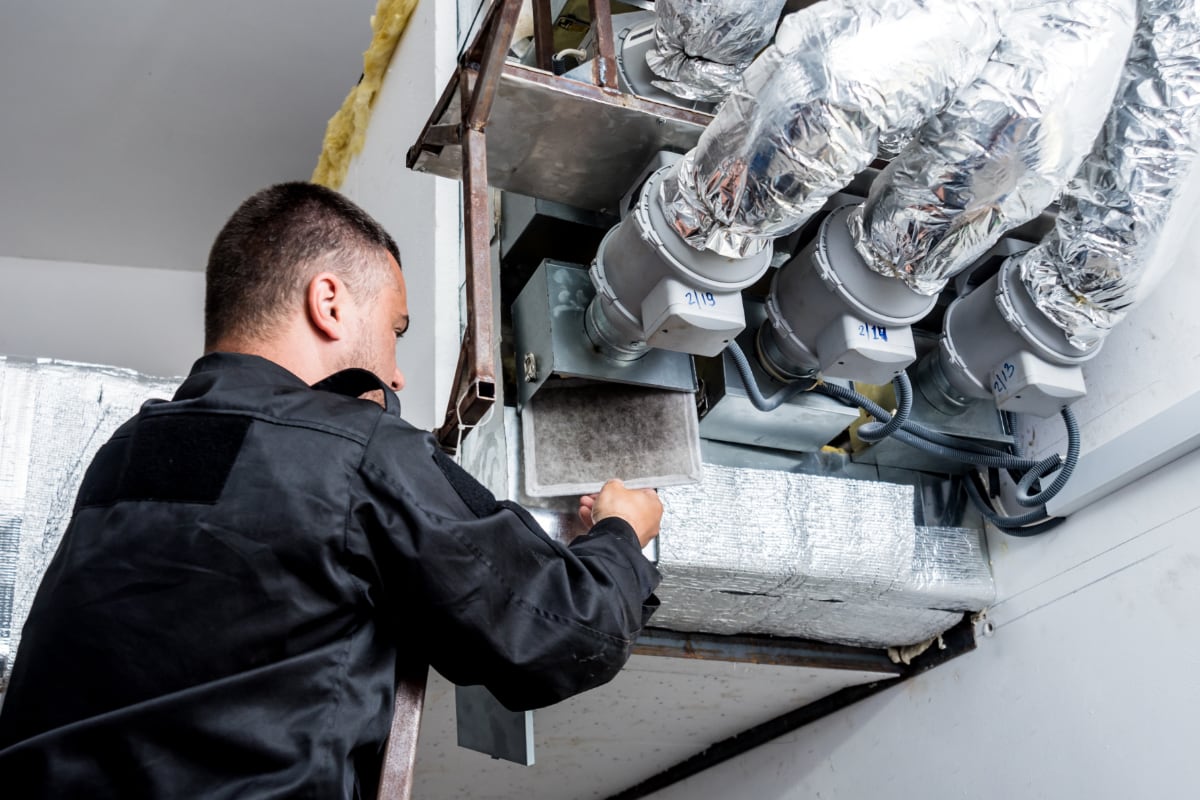 air duct technician removing a filter from a commercial vent unit