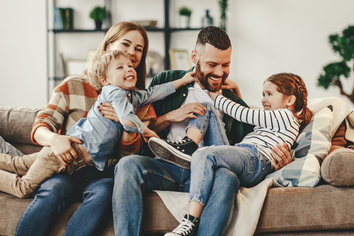 family of four on living room couch hugging and giggling