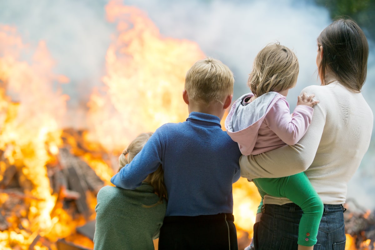 family with their backs to the camera standing in front of an inferno