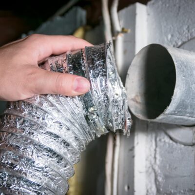 dryer vent cleaning technician removing dryer vent tubing from wall