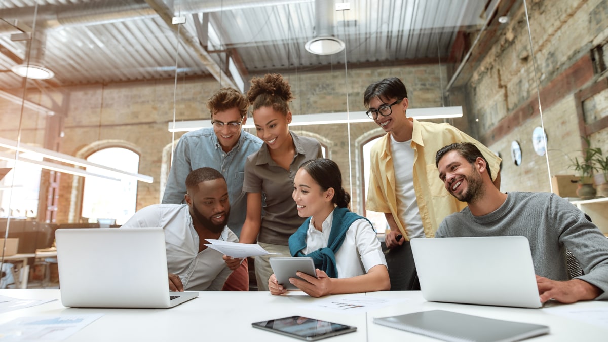 group of six racially diverse co-workers smiling and talking in a meeting