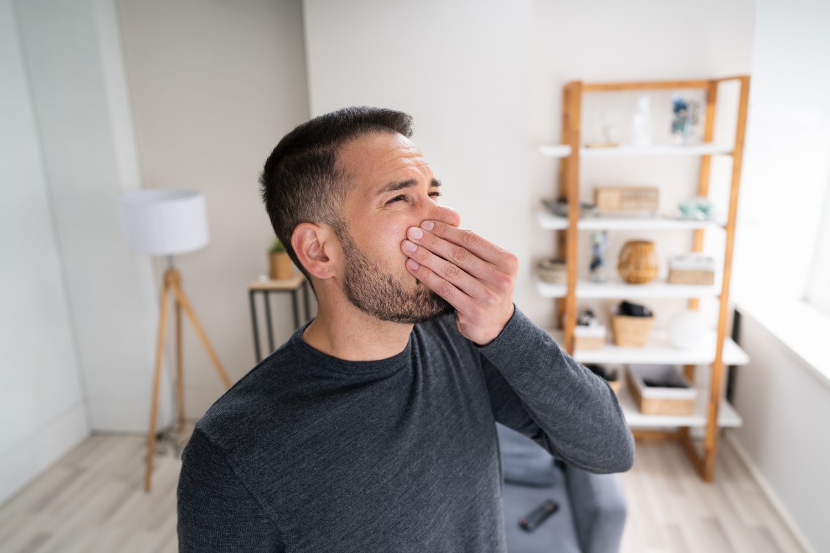 man standing in living room holding nose